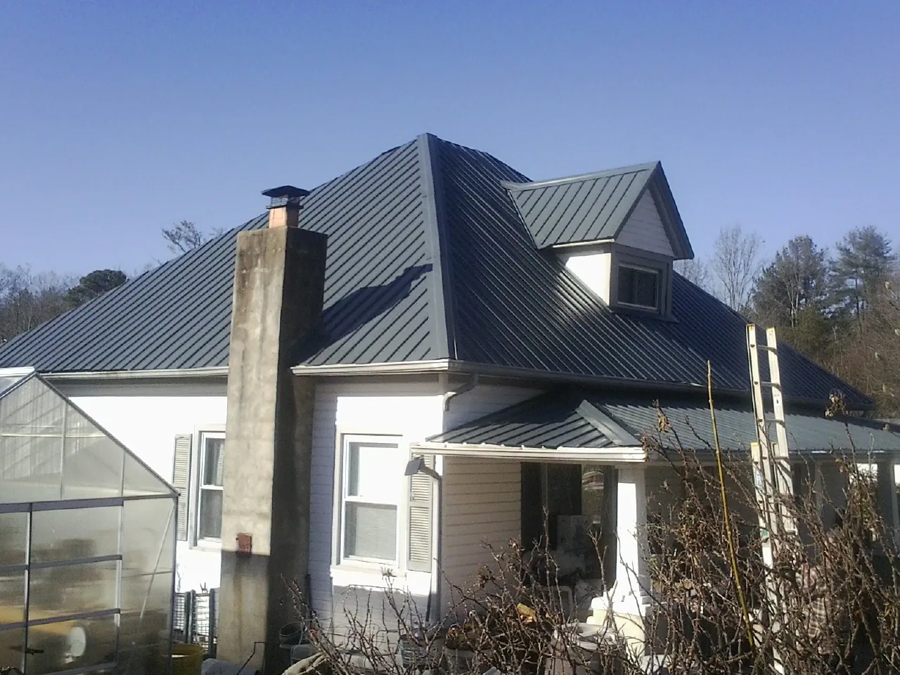 Dark blue standing seam metal roof on a white farmhouse with dormer — Slate & Tile Roof Repair by Roofing Brothers in Mt Baldy