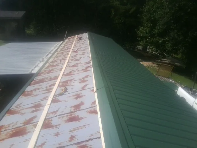 Old rusted panels beside newly installed green metal roofing — Wind Damage Roof Repair by Roofing Brothers in Mt Baldy