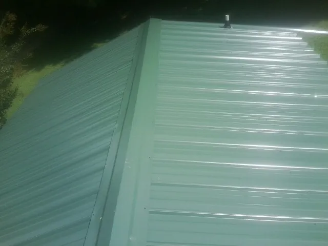 New green metal panels meeting at the ridge of a roof — Flat Roof Repair work by our crew in Mt Baldy