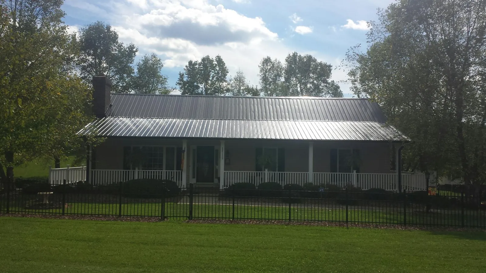 Gray metal roof on a brick ranch with a full width front porch — Gutter Guard Installation work by our crew in Mt Baldy