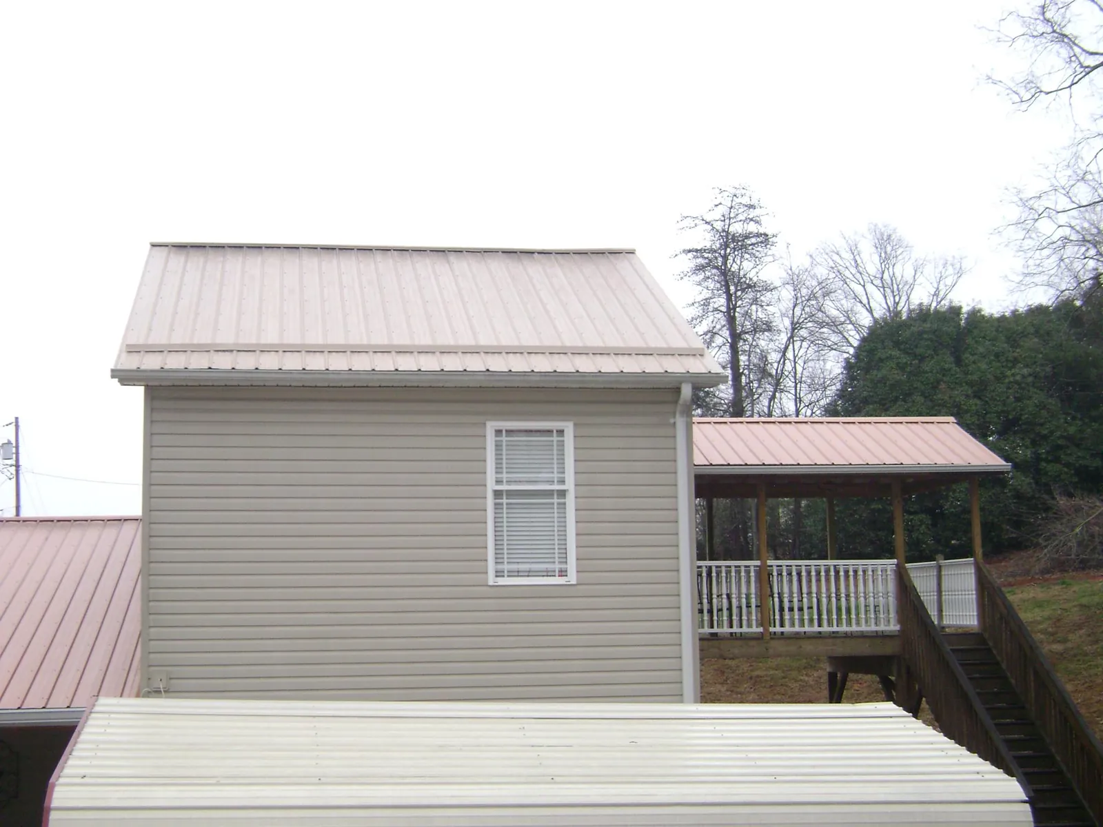 Tan metal roofs on a two story addition and attached porch, from a Roof Replacement job in Mt Baldy